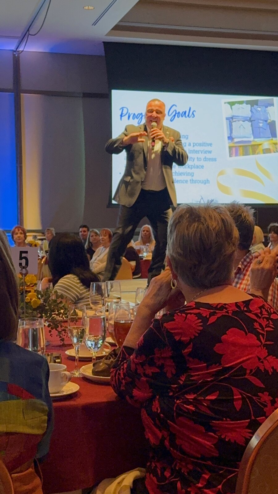 Pete Chryss speaking on stage at a nonprofit luncheon